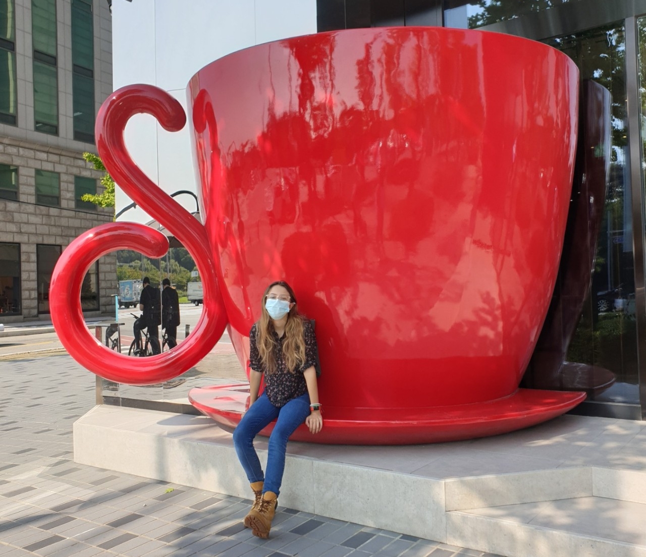 Masked student sitting with public art in Korea
